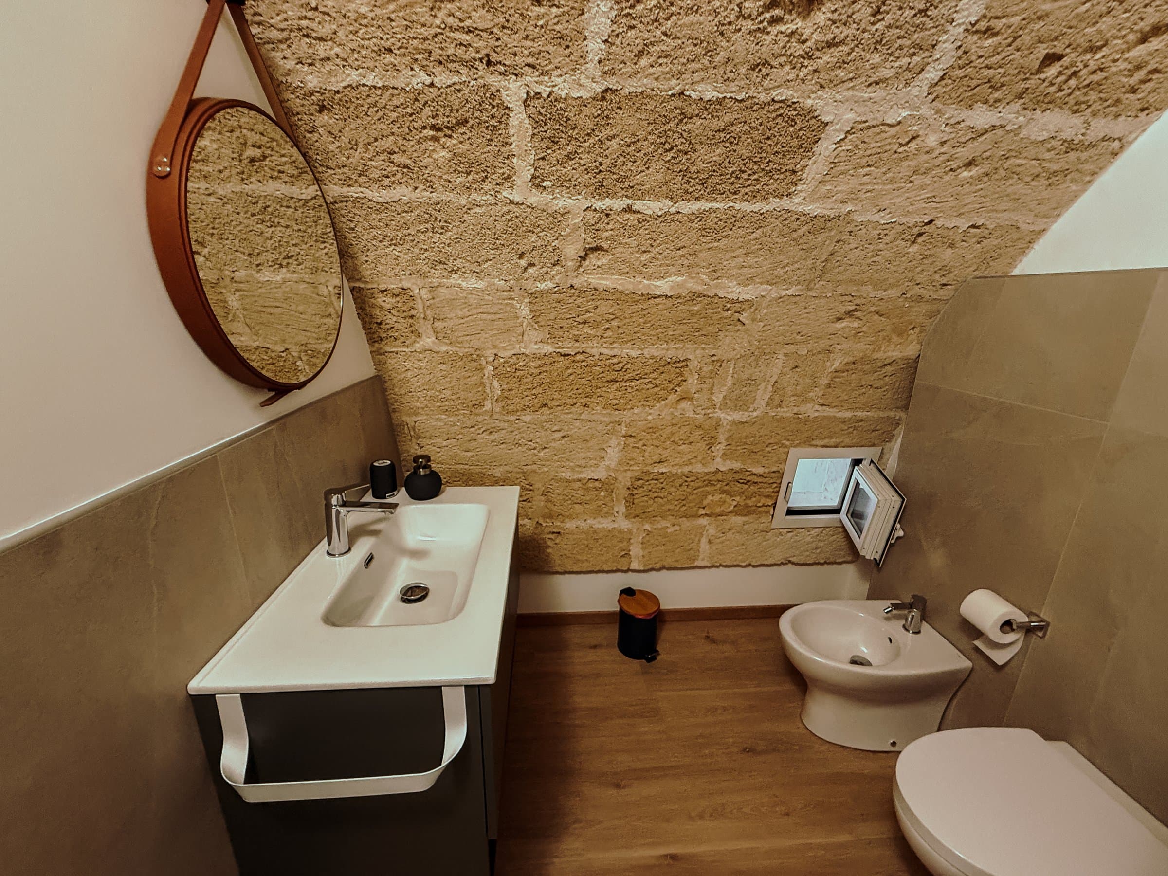 Bagno con specchio rotondo, lavabo e bidet